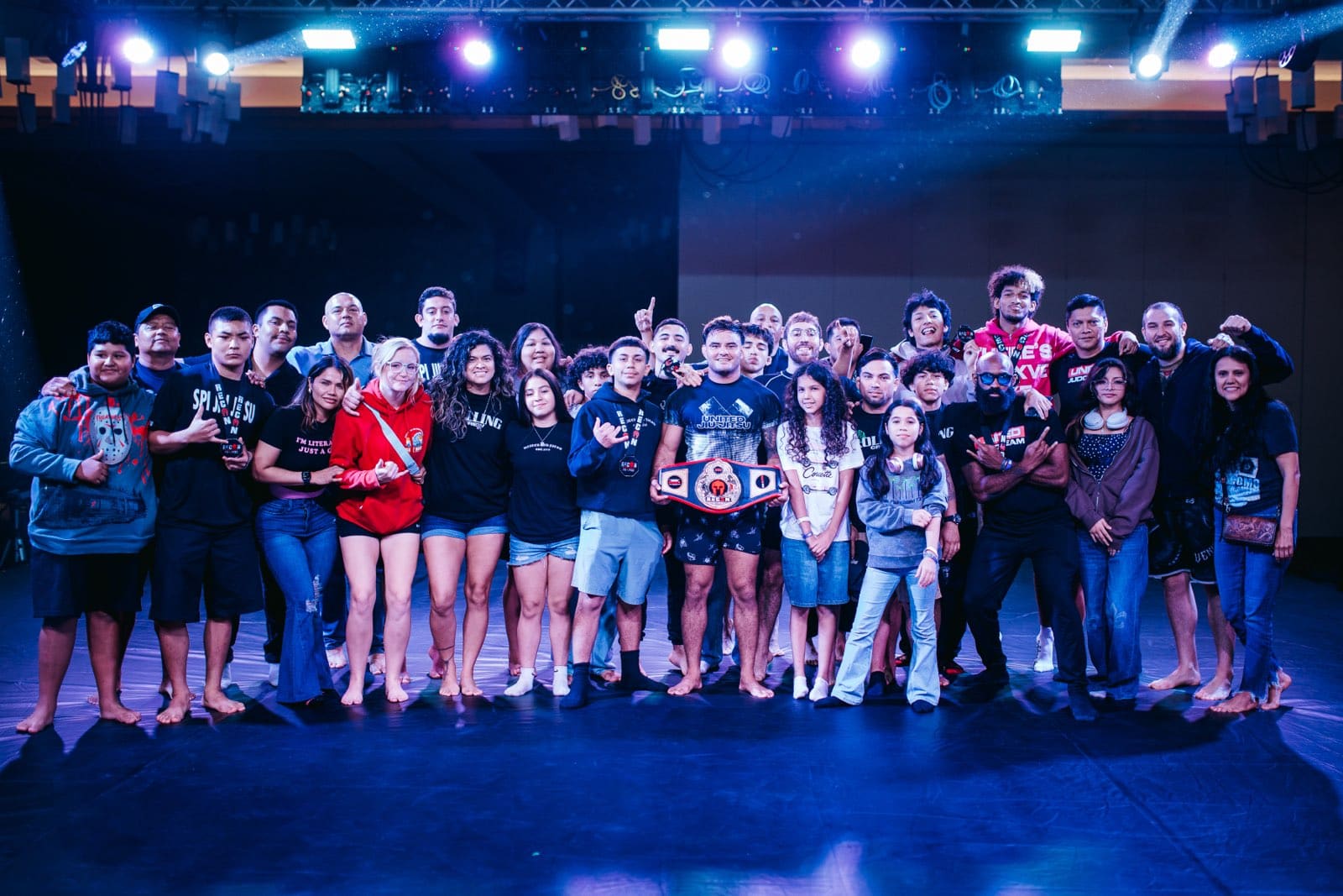 The SPI Jiu Jitsu team together after a competition, holding a championship belt.